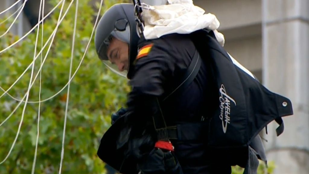 Desfile del Día de la Hispanidad: El paracaidista que lleva la bandera se engancha a una farola