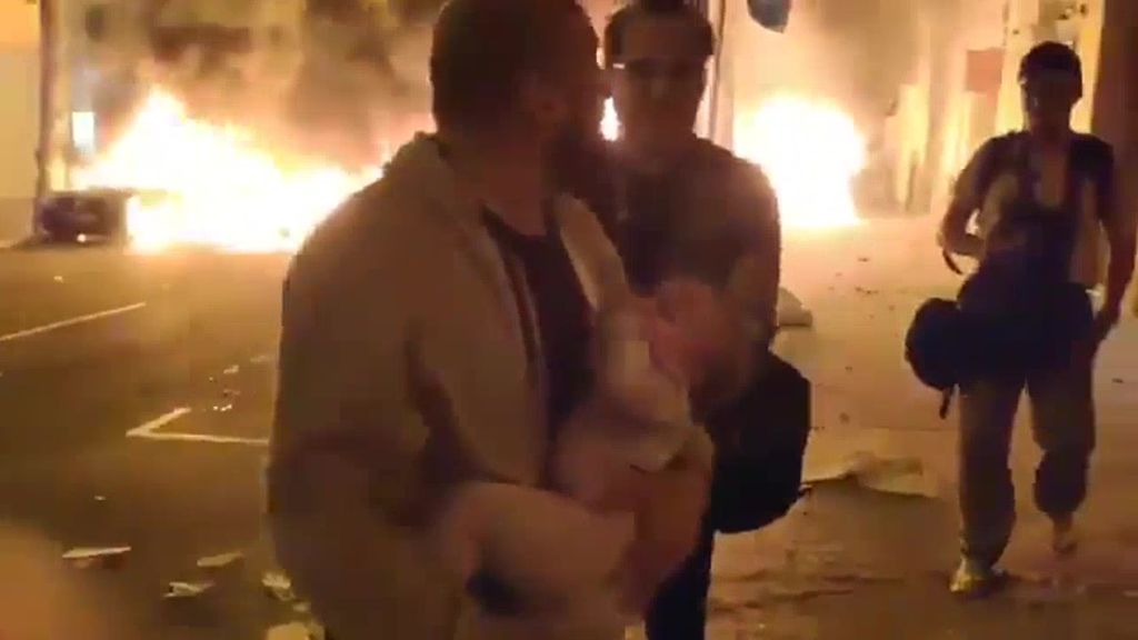 Un padre sale a la calle con su hijo en brazos huyendo de las llamas provocadas por los CDR en Barcelona