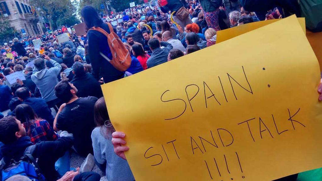 Manifestantes con un cartel en el que dice: "España: siéntate y habla"