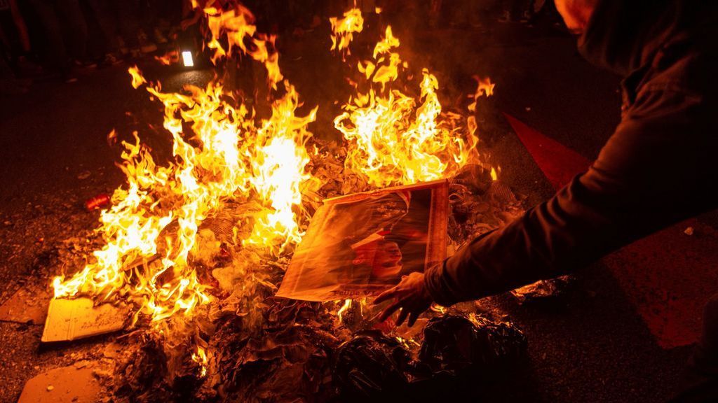 Manifestantes hacen una hoguera con fotos del rey en Barcelona
