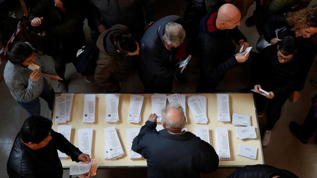Varias personas eligen papeleta en un centro electoral de Madrid