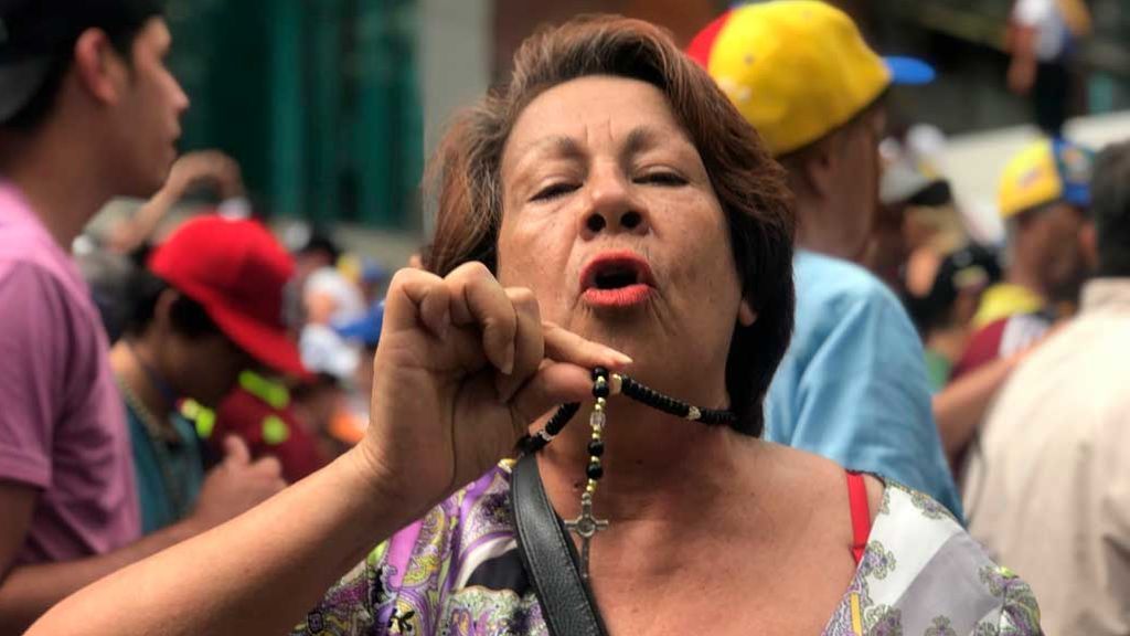 Mujer muestra un rosario frente a la embajada de Bolivia en Caracas