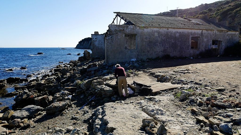Un pescador prepara su caña en las ruinas de la ballenera