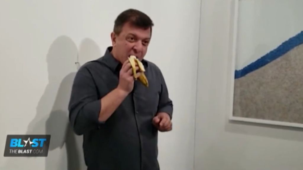Un artista se come la banana pegada a la pared con cinta americana de la feria de arte de Miami