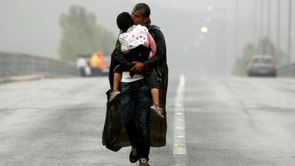 Un refugiado con su hija en brazos en la frontera de Macedonia