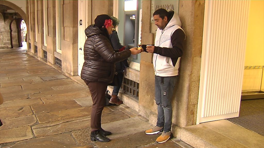 Chus, entregando chocolate y panetone a un hombre que pide en la calle