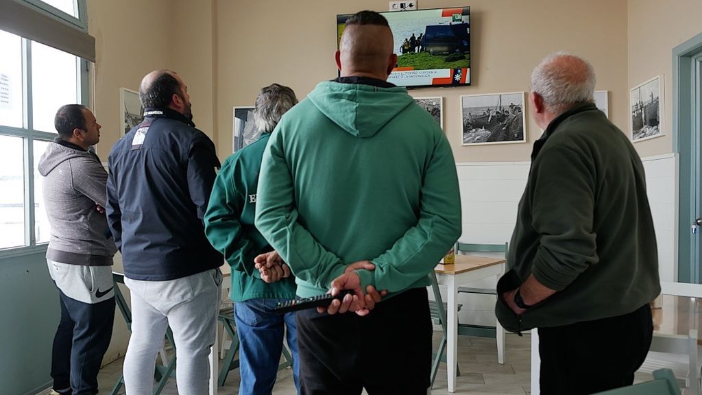 Un grupo de pescadores sigue las noticias en el puerto de Tarifa