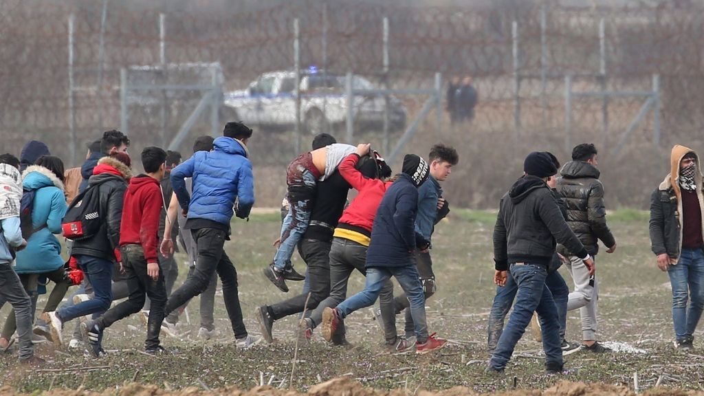 Migrantes trasladan a un hombre herido y huyen del gas lacrimógeno en la frontera de Grecia y Turquía