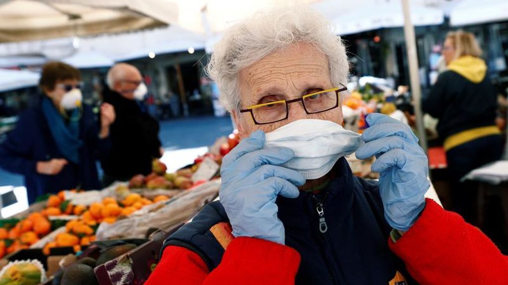 Una mujer usa mascarilla en un mercado italiano
