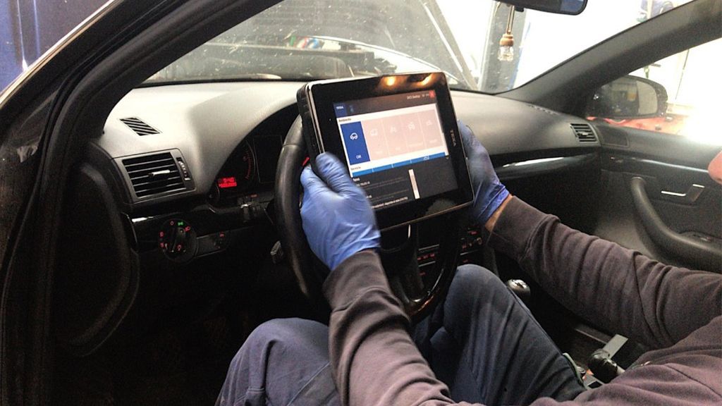 Un mecánico arreglando un coche hoy, en el interior de un taller