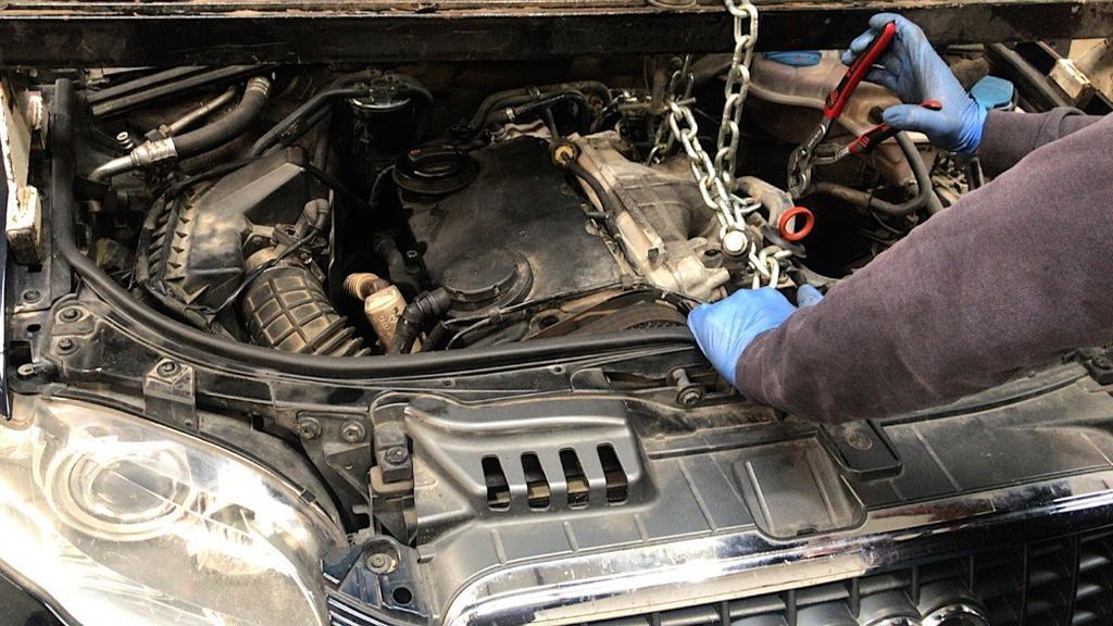 Un mecánico protegido con guantes arregla un motor