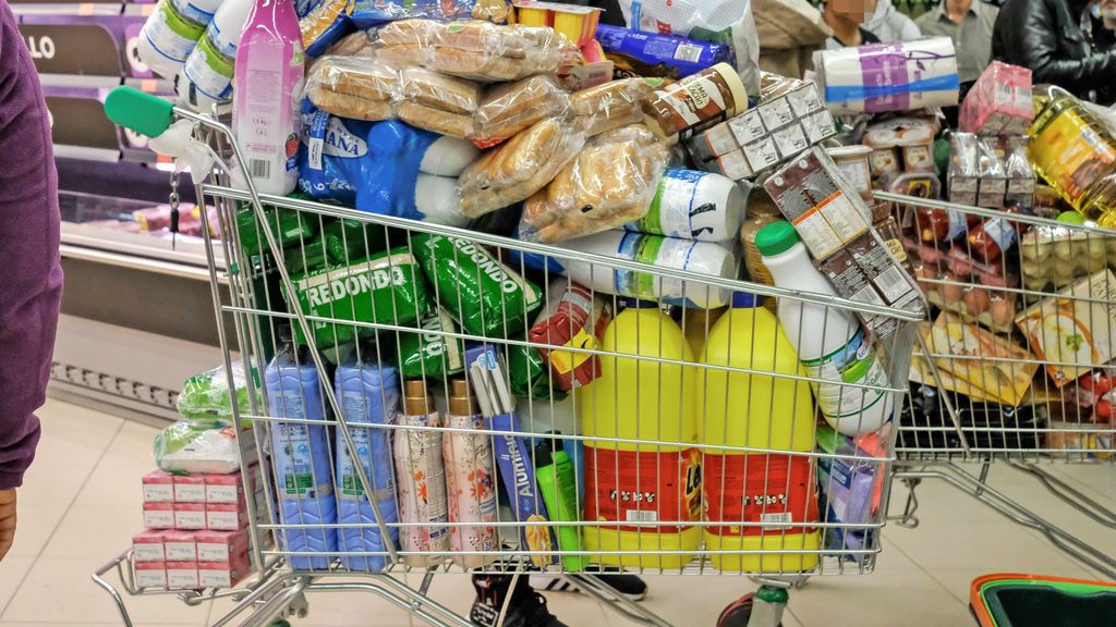 Un carro de supermercado a rebosar con varios productos de limpieza para el hogar.