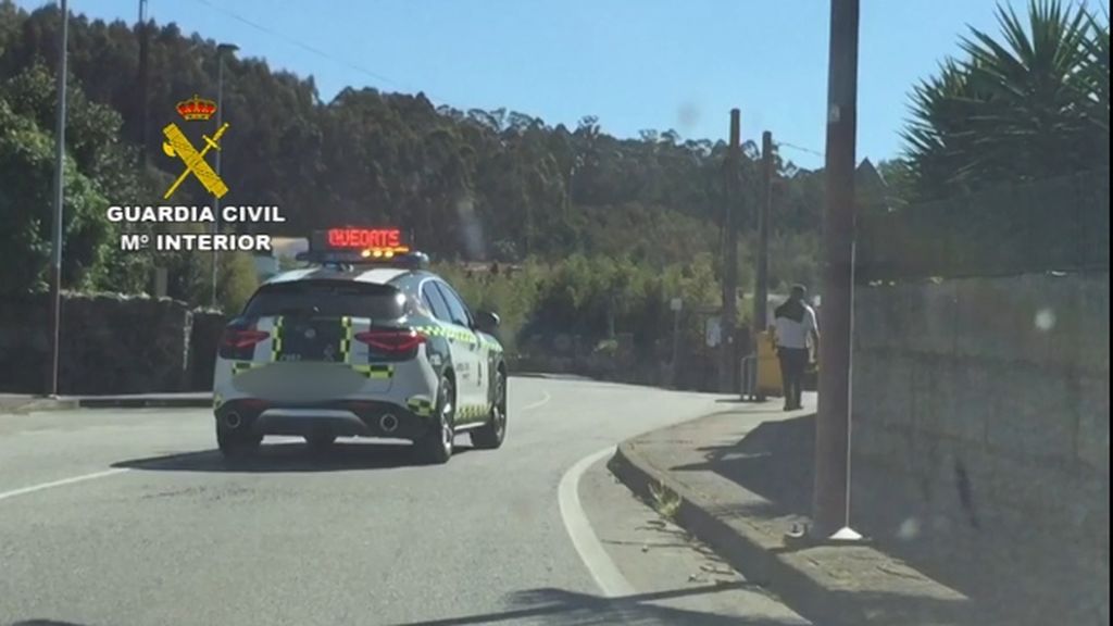 El peatón denunciado, caminando ante el coche de la Guardia Civil
