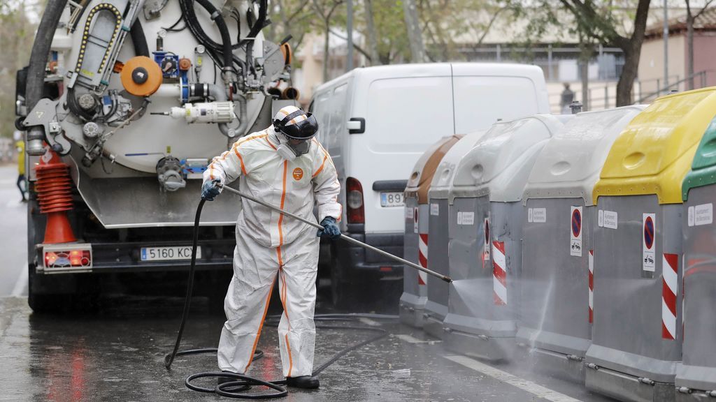 Operarios del servicio de limpieza desinfectan contenedores en Barcelona