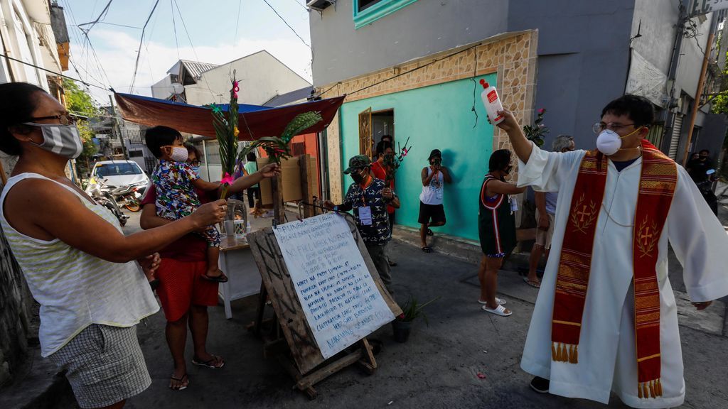 Un sacerdote echa agua bendita a los devotos en Filipinas