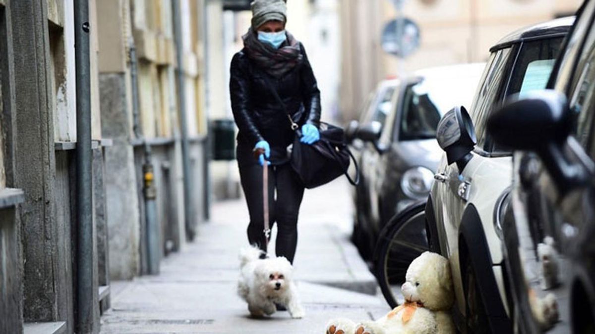 Una mujer con mascarilla pasea con su perro durante la crisis del coronavirus
