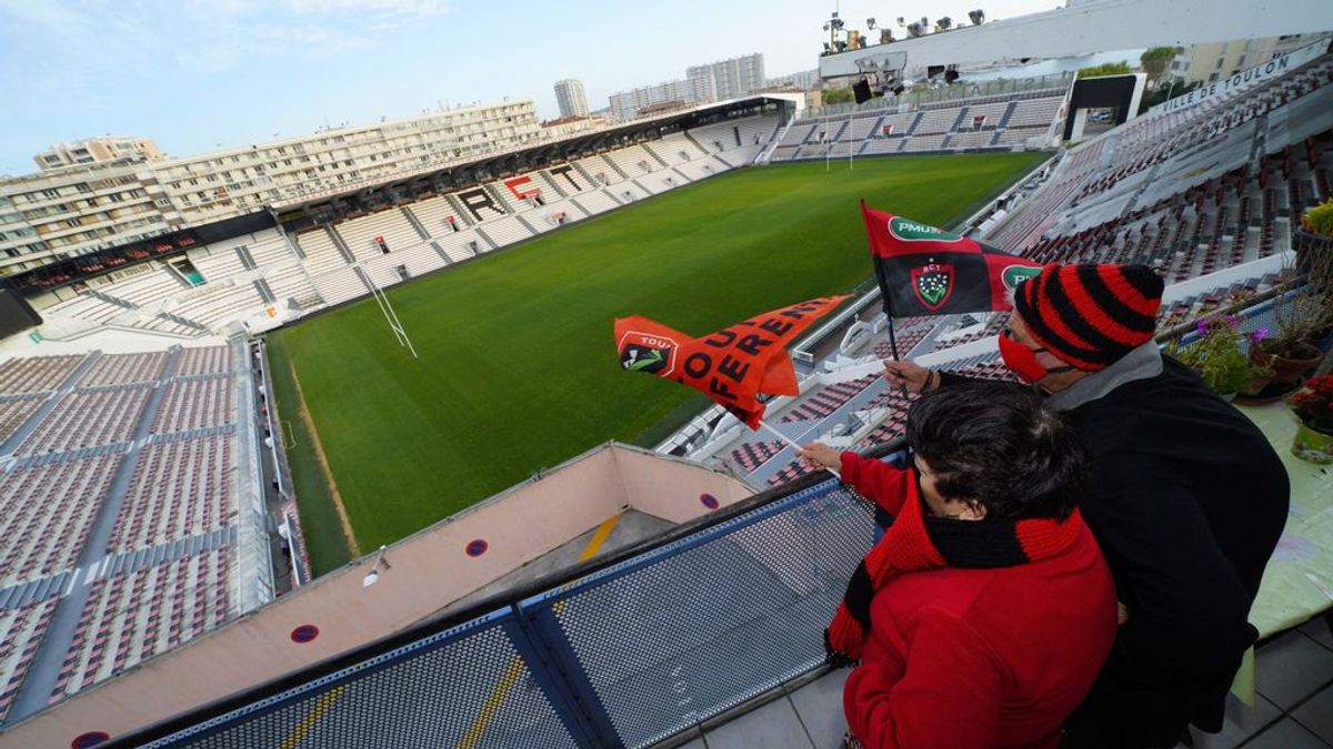 Dos aficionados simulan que animan en un estadio vacío.