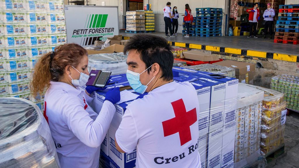 Voluntarios de la Cruz Roja reparten paquetes de alimentos y productos de higiene personal a familias necesitadas