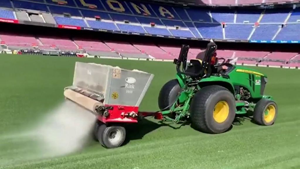 Un operario trabaja sobre el césped del Camp Nou.