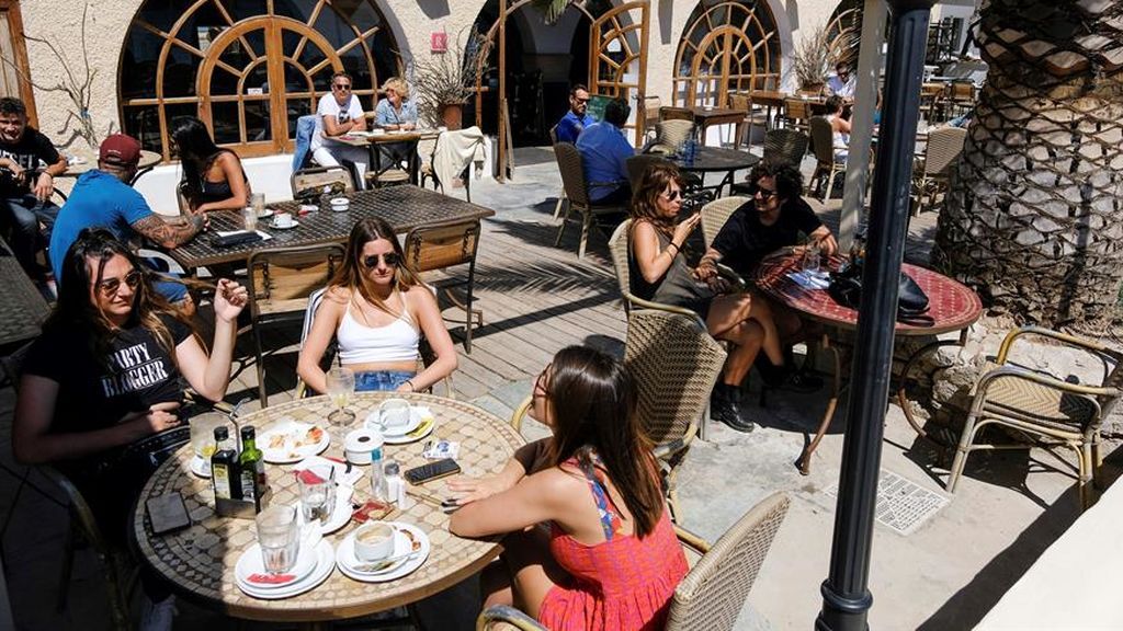 Varias personas desayunan en las terrazas de los bares de la playa de Talamanca en Ibiza