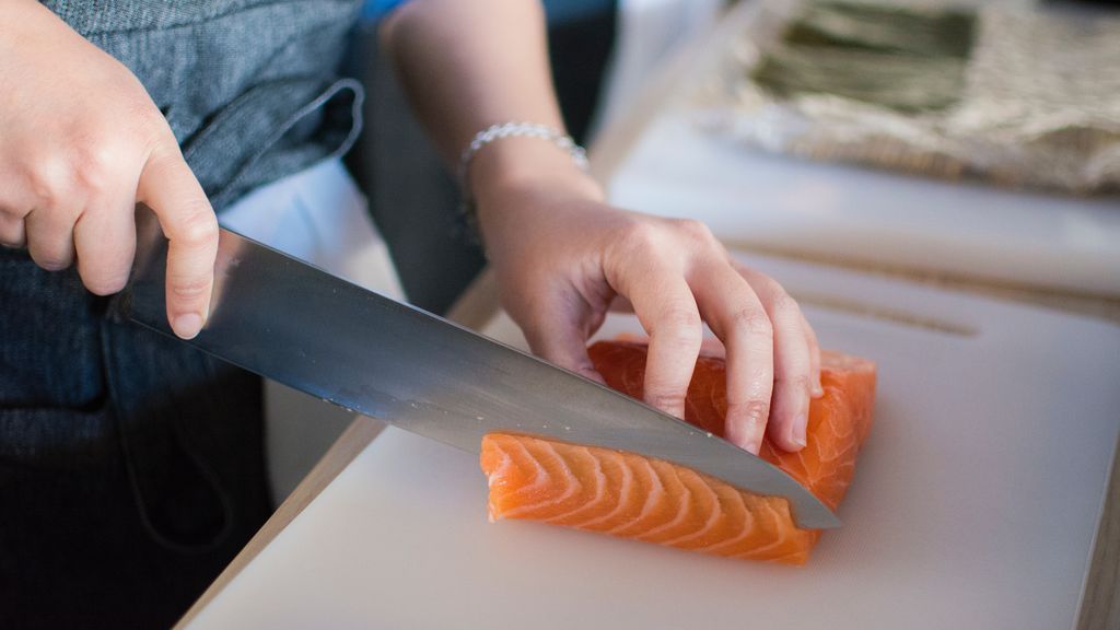 person-slicing-meat-on-white-chopping-board-1409050