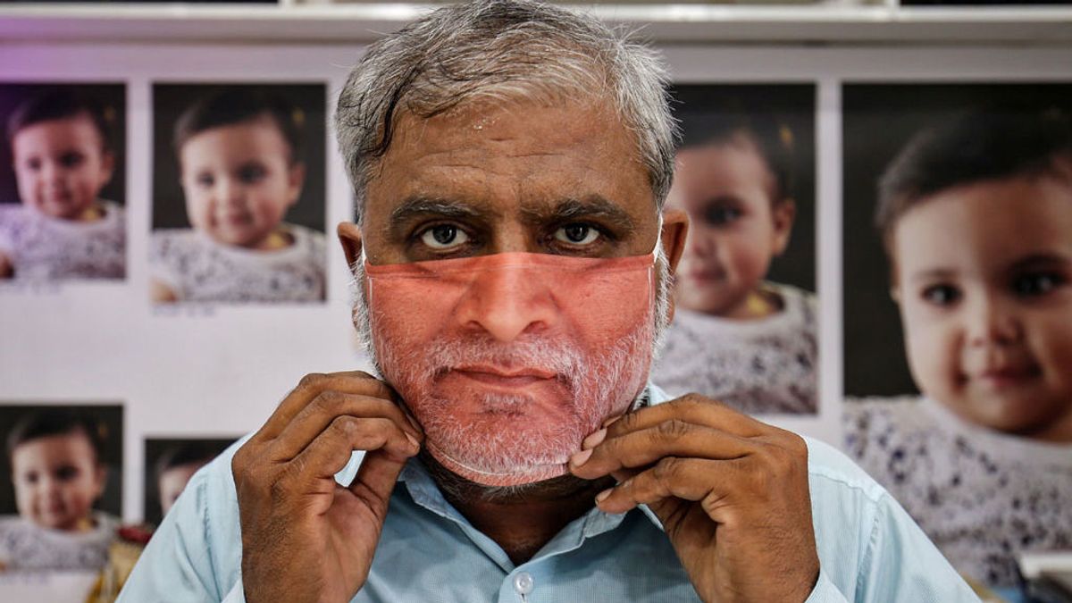 Un hombre prueba una mascarilla con su foto en Gandhinagar, India (mayo, 2020) Un hombre prueba una mascarilla con su foto en Gandhinagar, India (mayo, 2020)