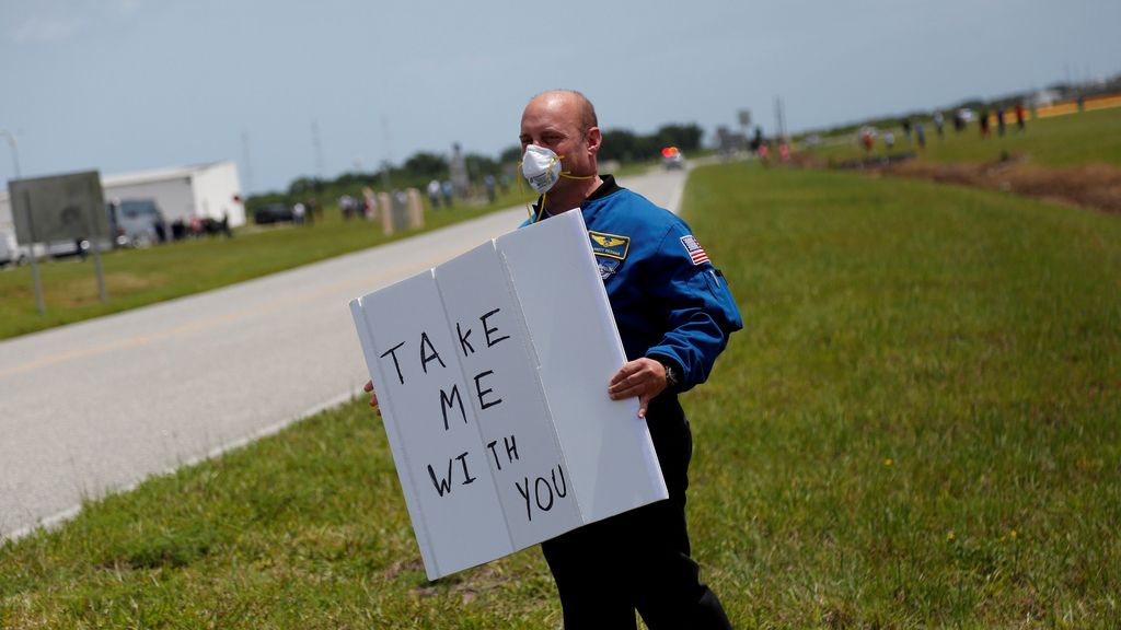 El exastronauta Garrett Reisman sostiene un cartel durante el lanzamiento de la Crew Dragon