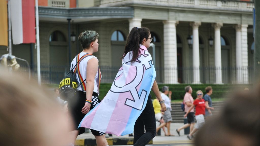Una chica lleva en los hombros la bandera trans