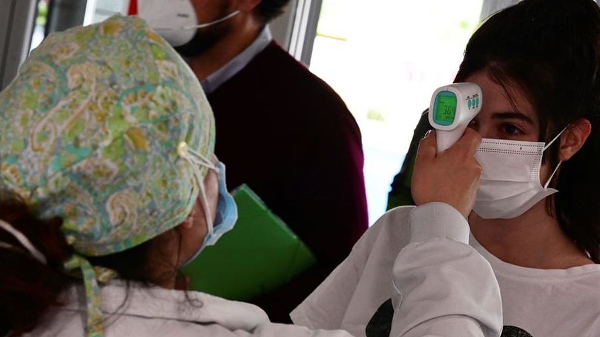 Un sanitario toma la temperatura a una mujer que accede al Hospital de Alcorcón en Madrid