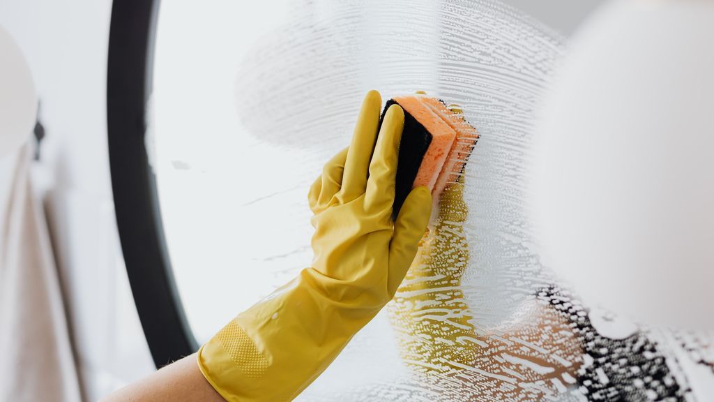 faceless-person-cleaning-mirror-with-sponge-4239146