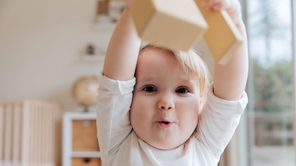 baby-in-white-onesie-holding-wooden-blocks-3933250