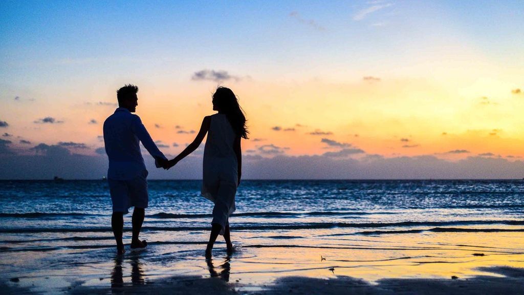 man-and-woman-holding-hands-walking-on-seashore-during-1024960