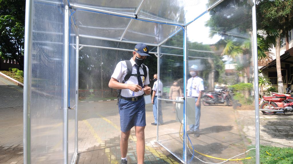 Un estudiante pasa por una cámara de desinfección en Salatiga