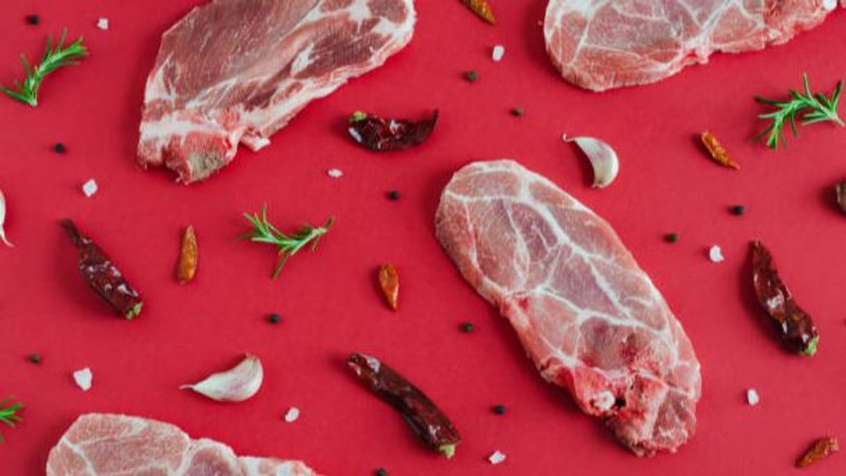 Raw pork steaks with spices on red background. Flat lay. Raw pork steaks with spices on red background. Flat lay.