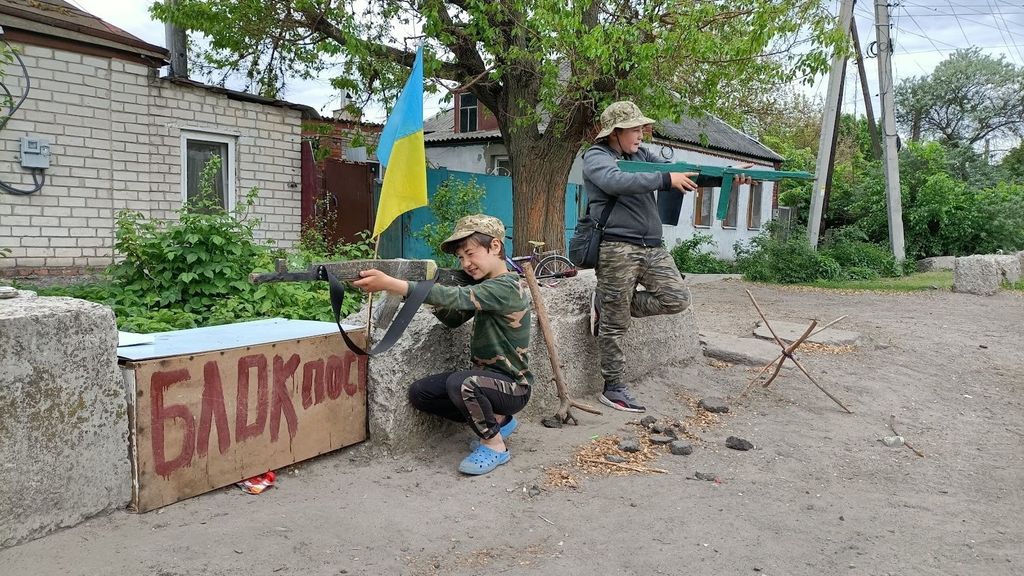 Jugando a la guerra: niños imitan un control militar en una calle de Járkov.