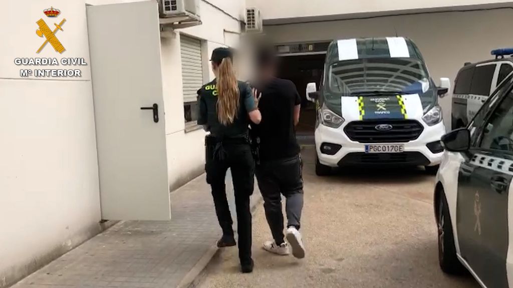 Una agente conduce a otro de los detenidos