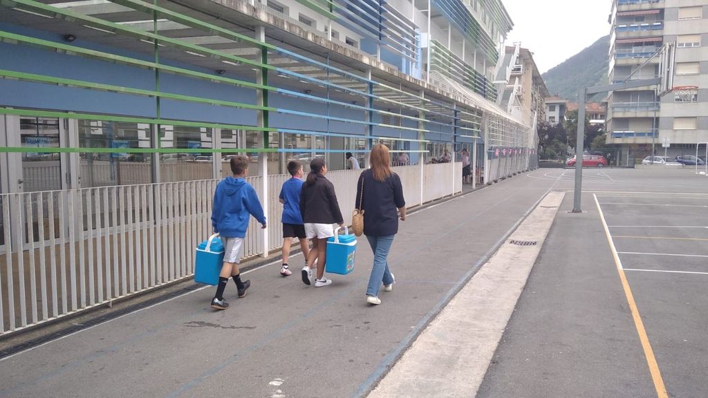 Los niños trasportando en neveras la comida.