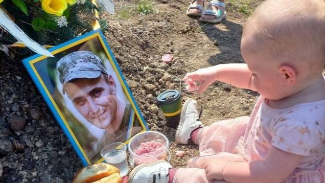 Una bebé de Ucrania celebra su cumpleaños en la tumba de su padre, muerto en combate