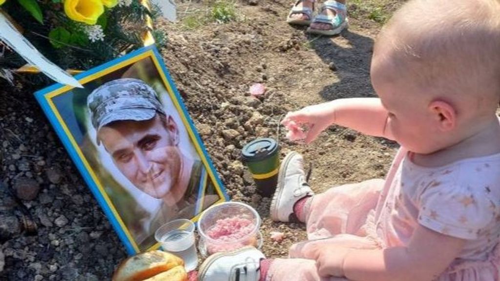 Una bebé de Ucrania celebra su cumpleaños en la tumba de su padre, muerto en combate