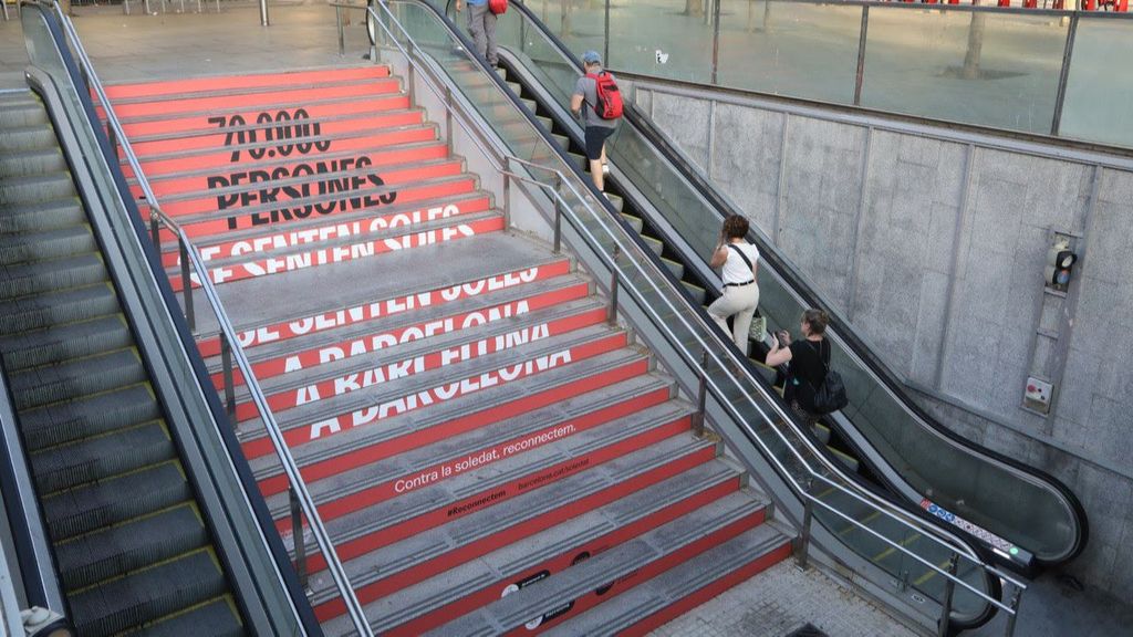 Un vinilado en un acceso al metro por la campaña del Ayuntamiento de Barcelona 'Contra la soledat, reconnectem'