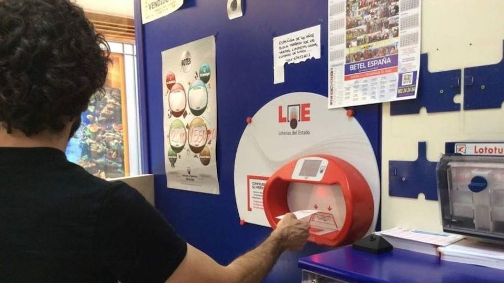 Imagen de archivo de un hombre comprobando un boleto en una administración de lotería