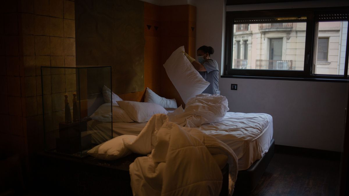 Una camarera de piso cambia las sábanas en una cama de hotel. Una camarera de piso cambia las sábanas en una cama de hotel.