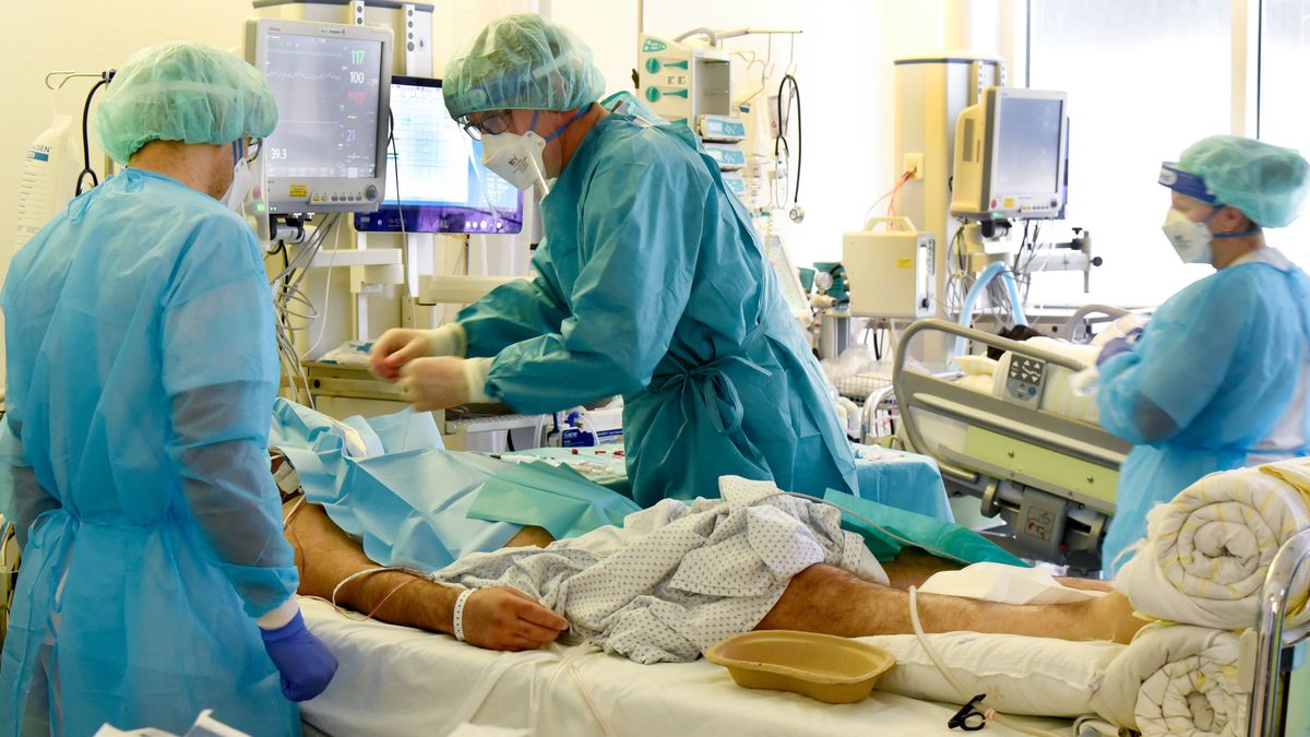 Varios sanitarios atienden a un paciente ingresado Varios sanitarios atienden a un paciente ingresado