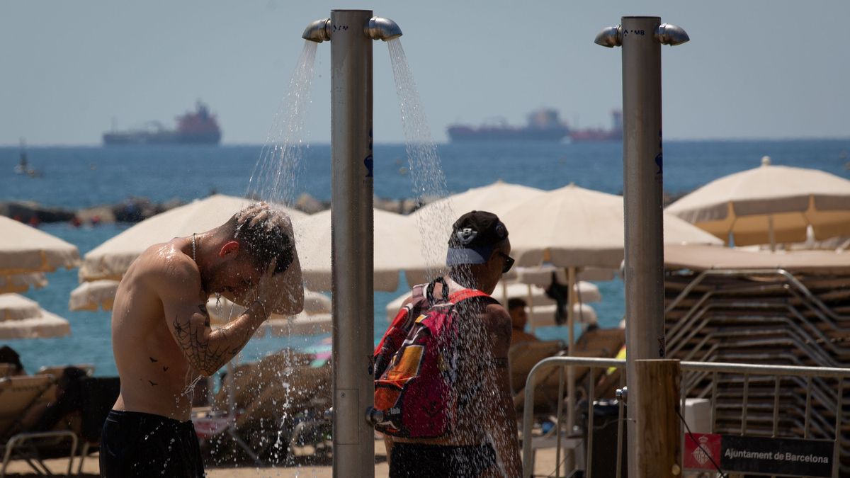 Varias personas se mojan en las duchas de la playa de la Barceloneta, a 13 de julio de 2022, en Barcelona, Catalunya (España)
