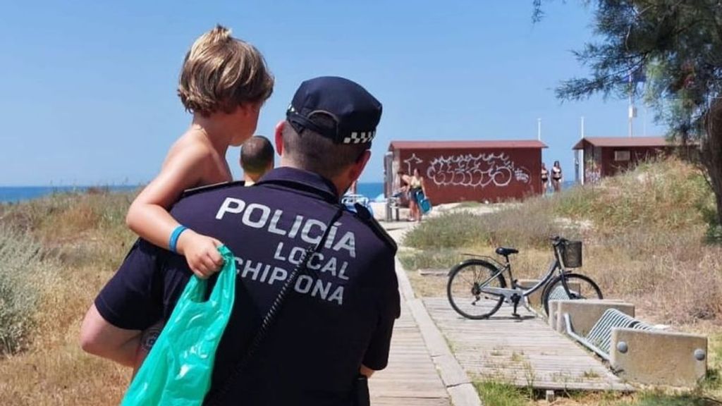 Alejandro, de 4 años, junto a uno de los agentes de la Policía Local de Chipiona, que acudió a recogerle a una playa de Chipiona tras perderse en Rota