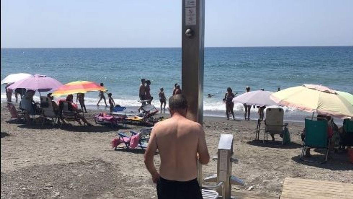 Un usuario de la playa de Algarrobo (Málaga) junto a una de las duchas de la playa. A 31 de julio de 2022. Un usuario de la playa de Algarrobo (Málaga) junto a una de las duchas de la playa. A 31 de julio de 2022.
