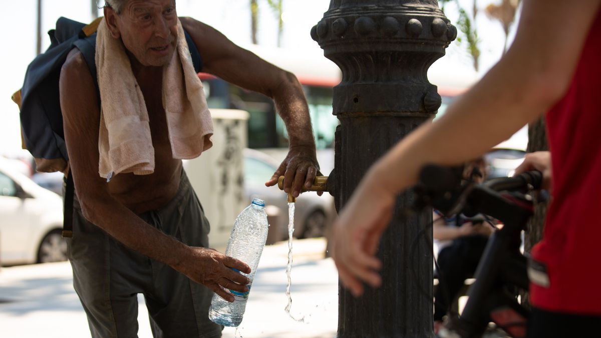 Un hombre rellena una botella de agua en una fuente en el parque de la Barceloneta