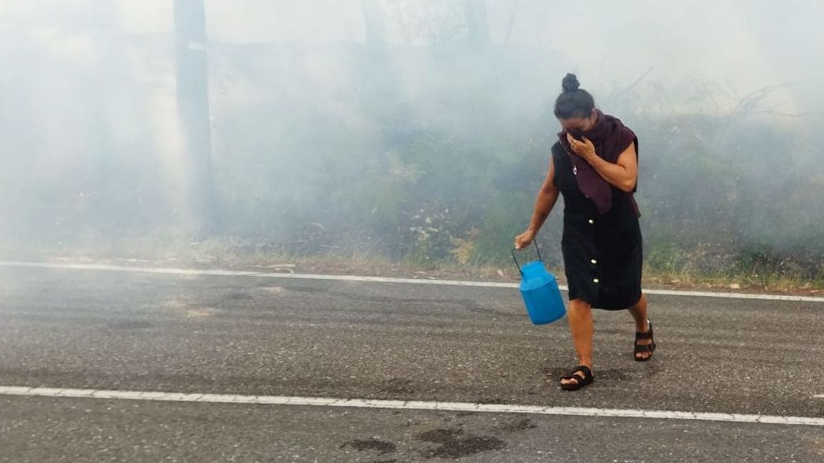 Una mujer se protege del intenso humo en el núcleo de Cea. Una mujer se protege del intenso humo en el núcleo de Cea.