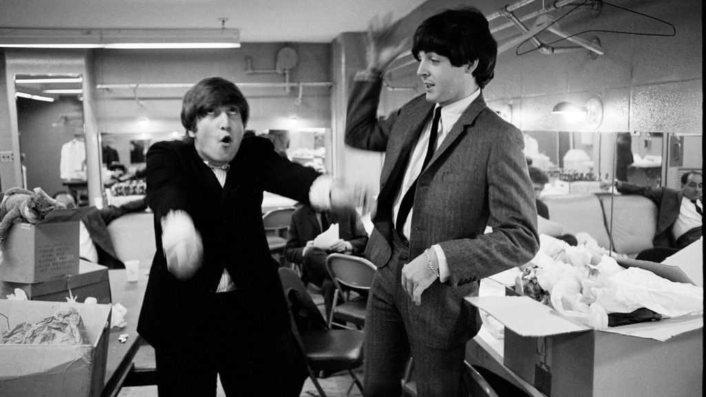 Los músicos John Lennon y Paul McCartney bromeando en el camerino