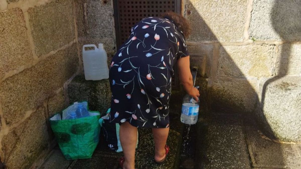 Una mujer rellenando botellas de agua. Una mujer rellenando botellas de agua.